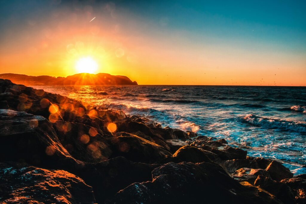 warm sunrise over the ocean with rocks in foreground