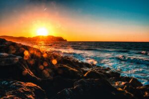 warm sunrise over the ocean with rocks in foreground